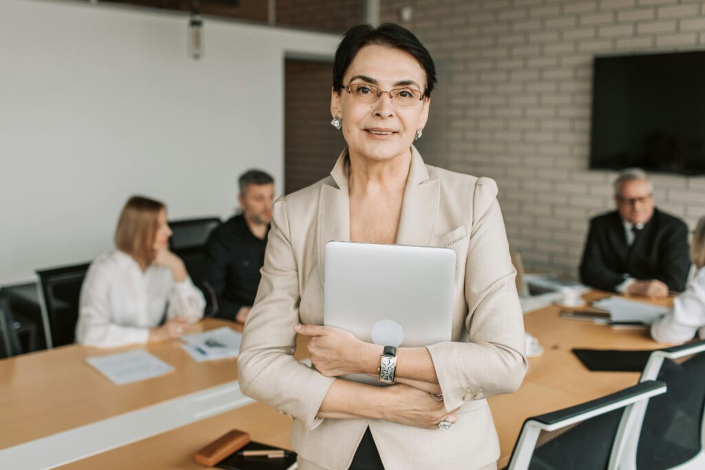 Confident businesswoman holding folder during a team meeting in modern office setting.